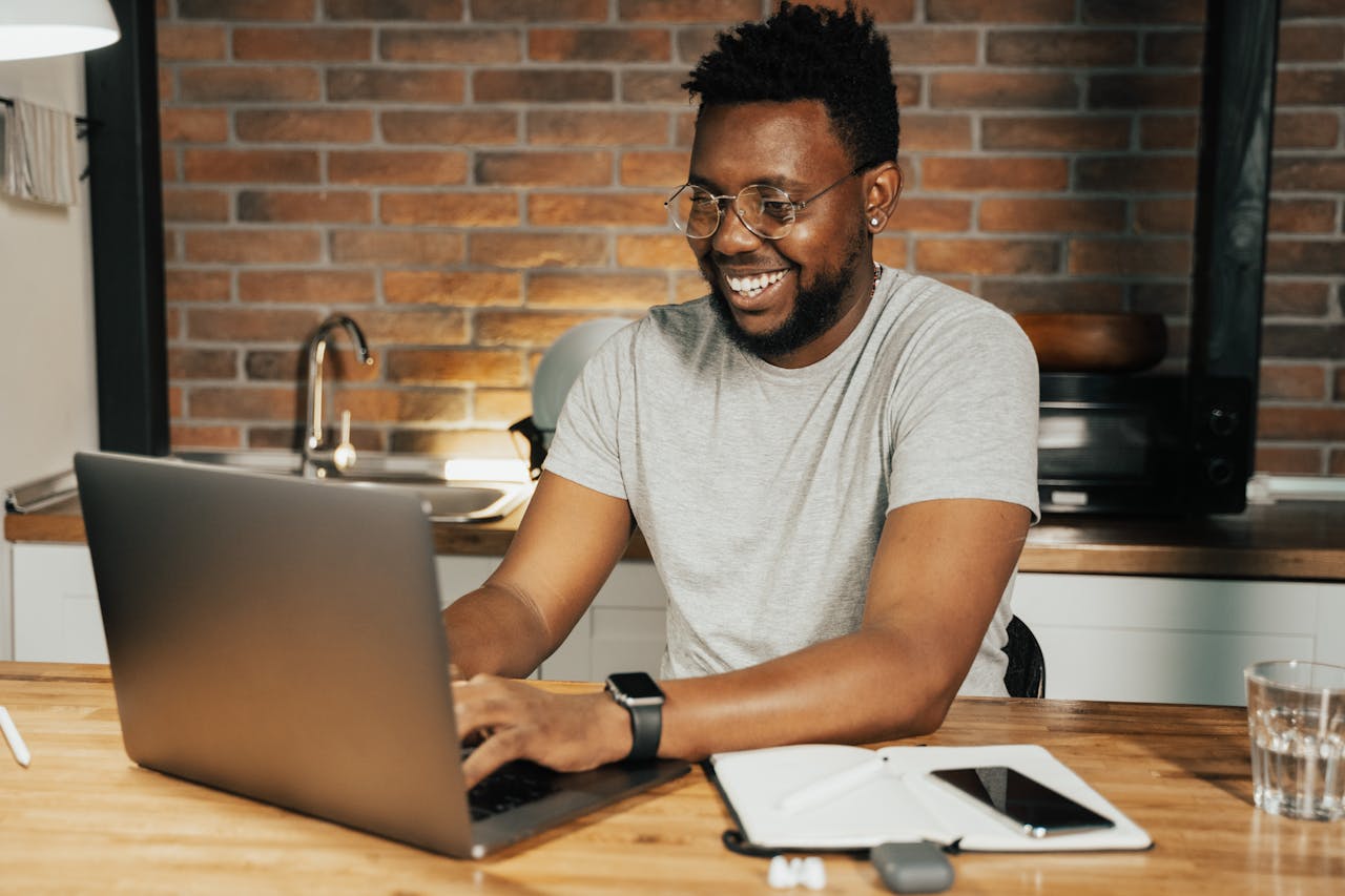 Mastering the First Impression: Your intriguing post title goes here African American man smiling while working remotely on laptop from home office